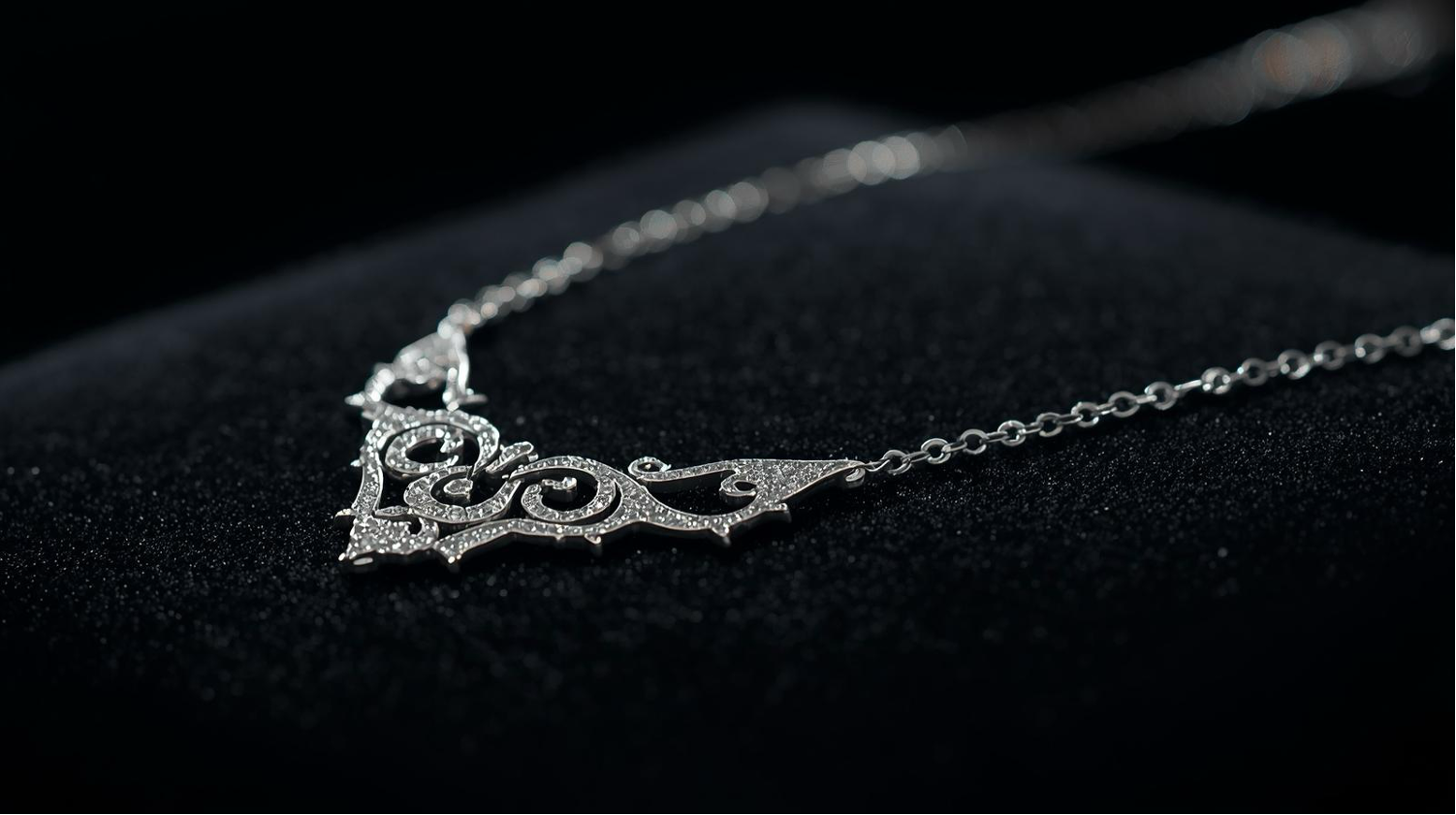 Stylish Silver Necklace with ornate V-shaped pendant displayed on a black velvet surface.