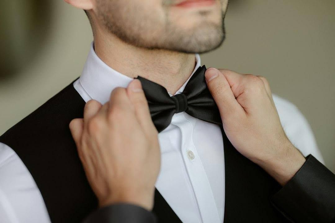 A man adjusts his bow tie