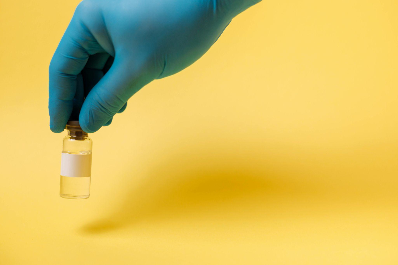 Hand in blue glove holding glass vial with blank label, by Thirdman on Pexels