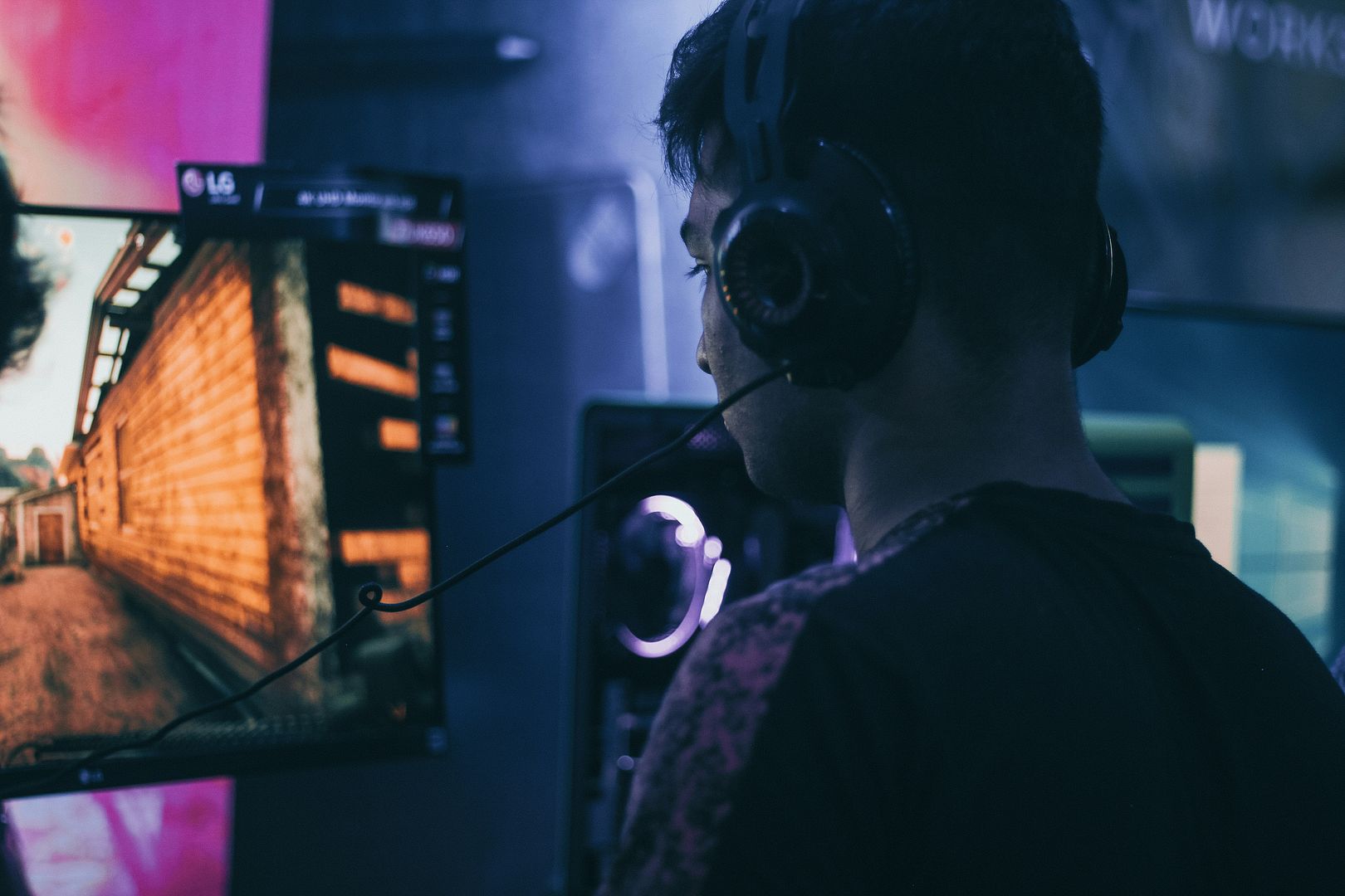 Person wearing headphones watching a competitive match on screen