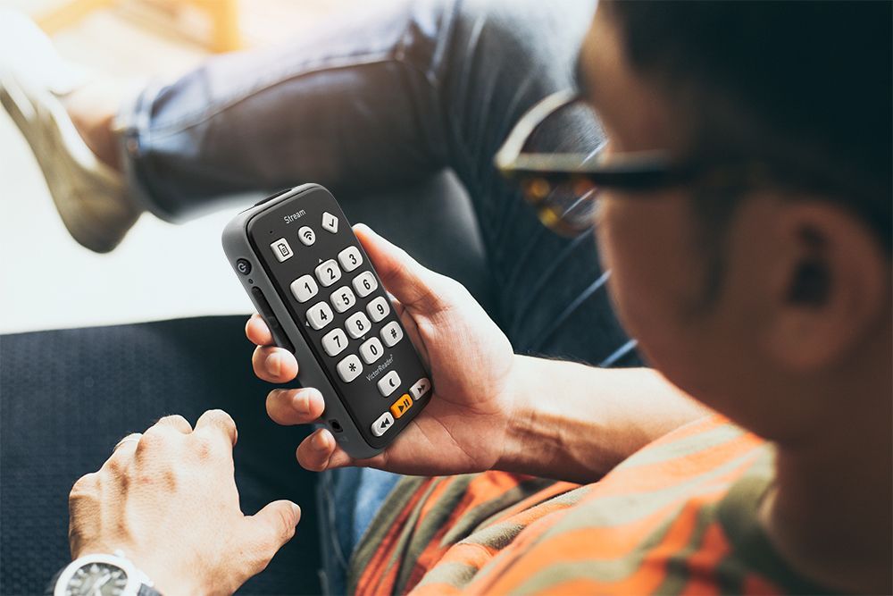 Un homme utilise le Victor Reader Stream 3 pour écouter des livres audio