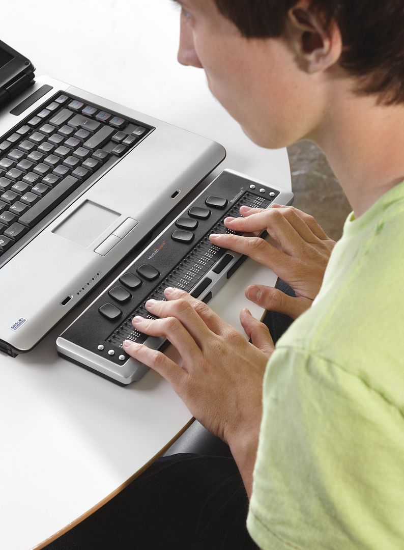 Un adolescent utilise la règle de lecture en braille en classe