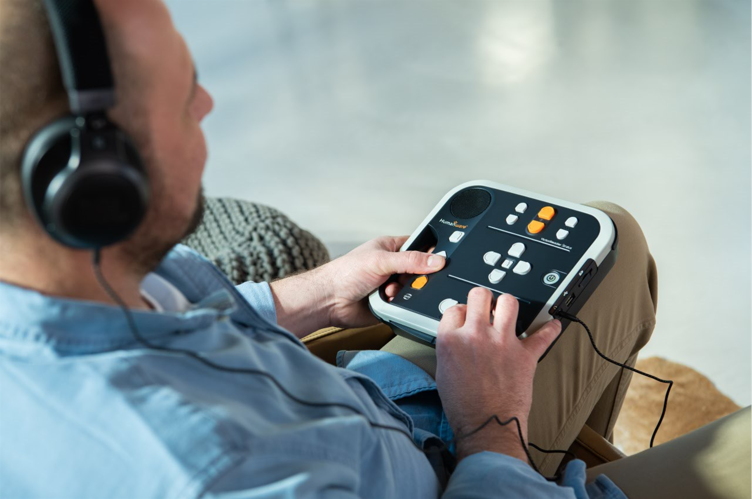 Un homme utilise le Victor Reader Stratus pour écouter des livres audio