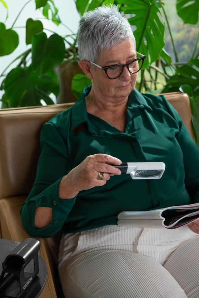 Oudere vrouw leest een document met een vergrootglas