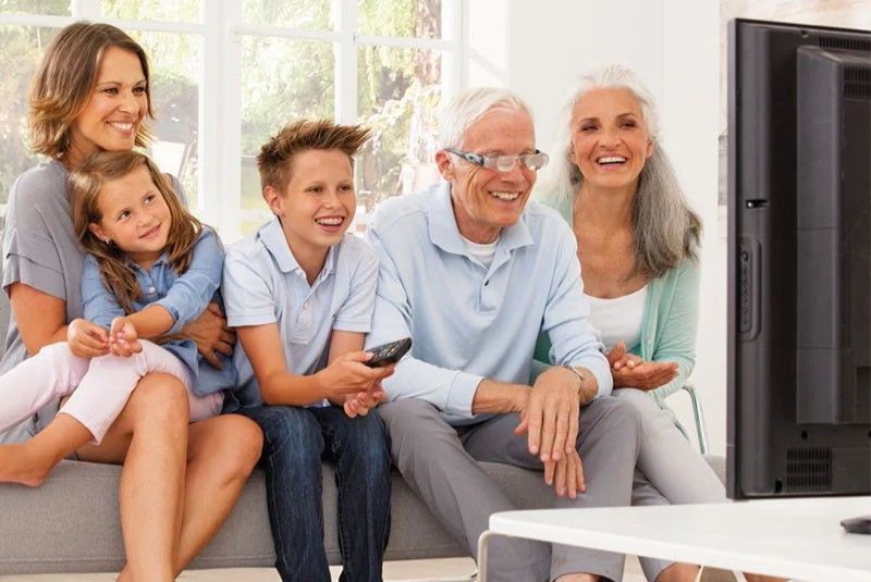 Un homme regarde la télévision en famille grâce aux lunettes max-tv