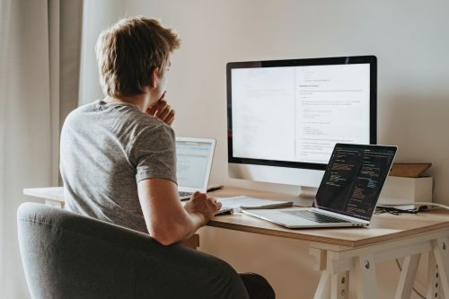 Man kijkt naar groot scherm en gebruikt laptop