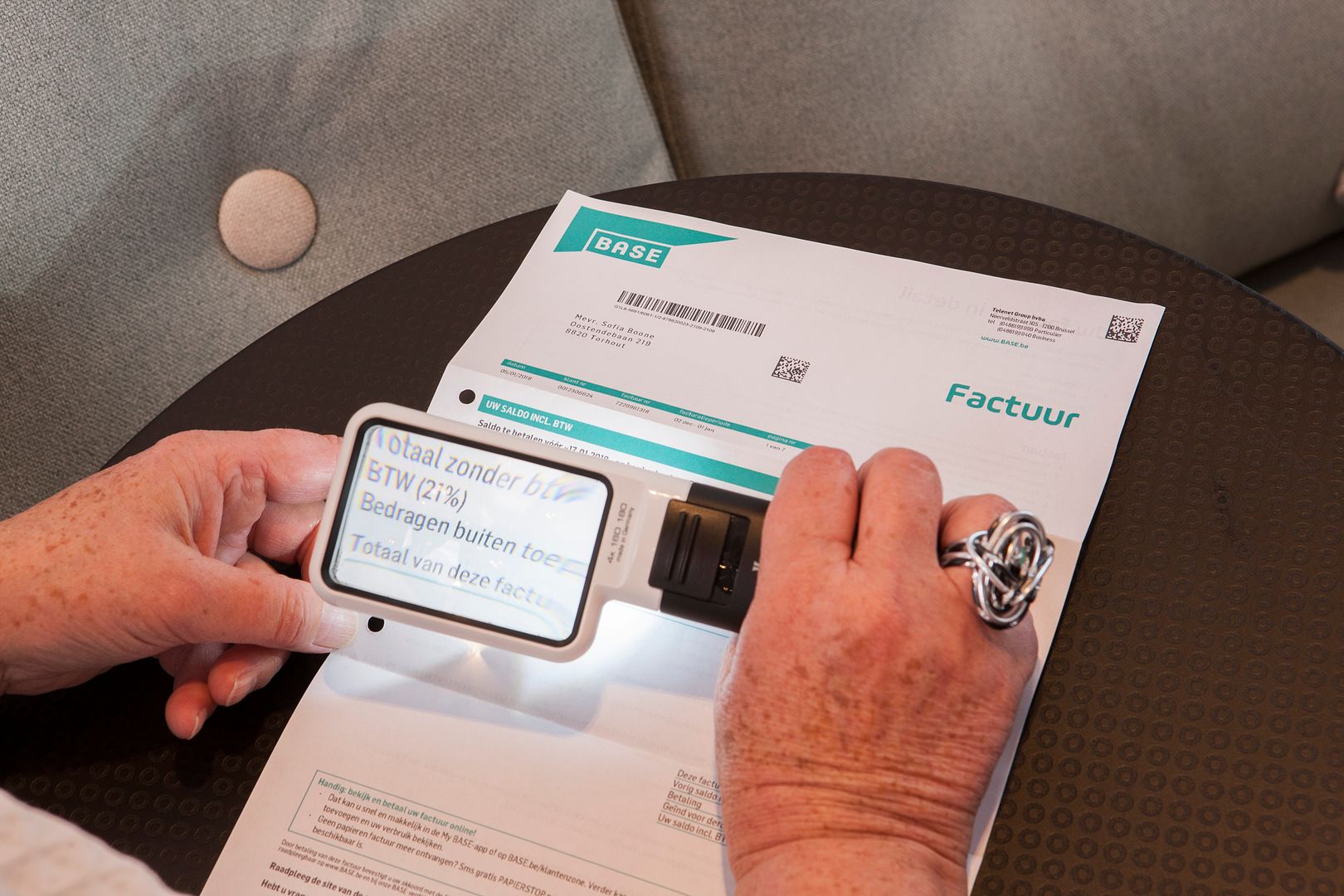 Une femme utilise une loupe optique pour vérifier une facture