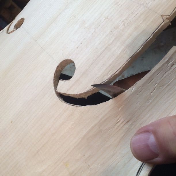 Using a knife to refine the f-holes on a five-string double bass.