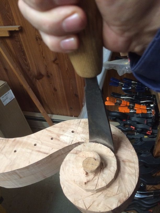 Removing waste wood from the 5-string double bass scroll, using a gouge.