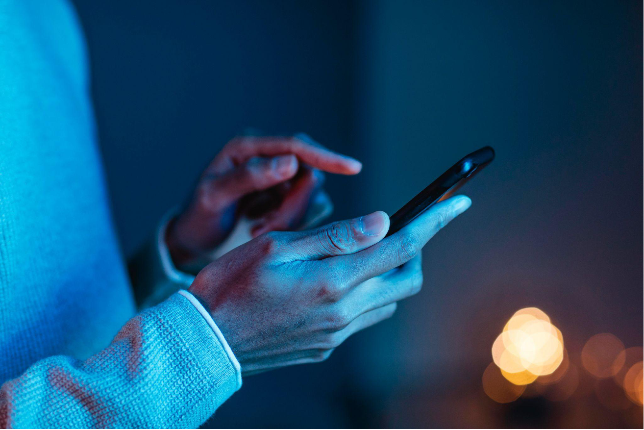 A person using a smartphone in a dimly lit room.