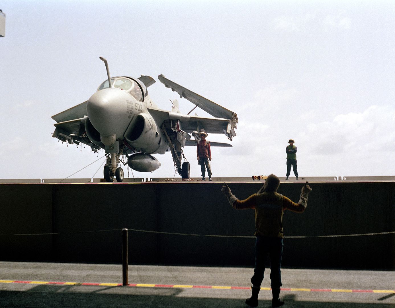 A Crew Member On An Elevator Signals To Flight Deck Crew Members As They Stand Beside As A 6E Intruder Aircraft During A General Quarters Drill Aboard The Aircraft Carrier USS KITTY HAWK