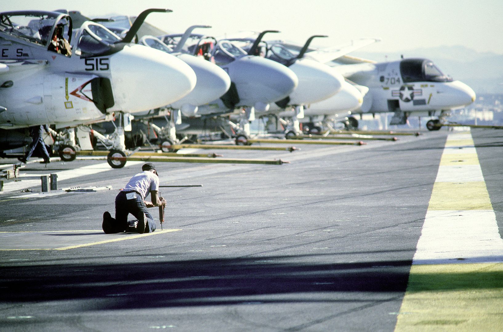 A Crew Member Performs Routine Maintenance On The Flight Deck Of The Aircraft Carrier USS KITTY HAWK