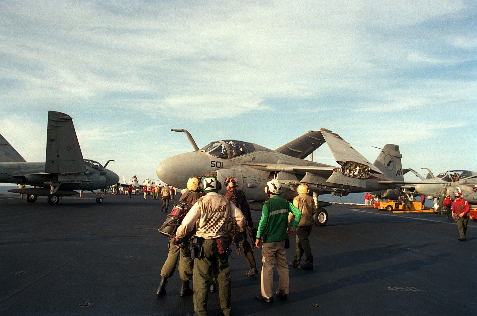 An Attack Squadron 35 A 6E Intruder Aircraft Taxis On The Flight Deck As MD 3A Tow Tractors Position Other Intruders Aboard The Aircraft Carrier USS SARATOGA