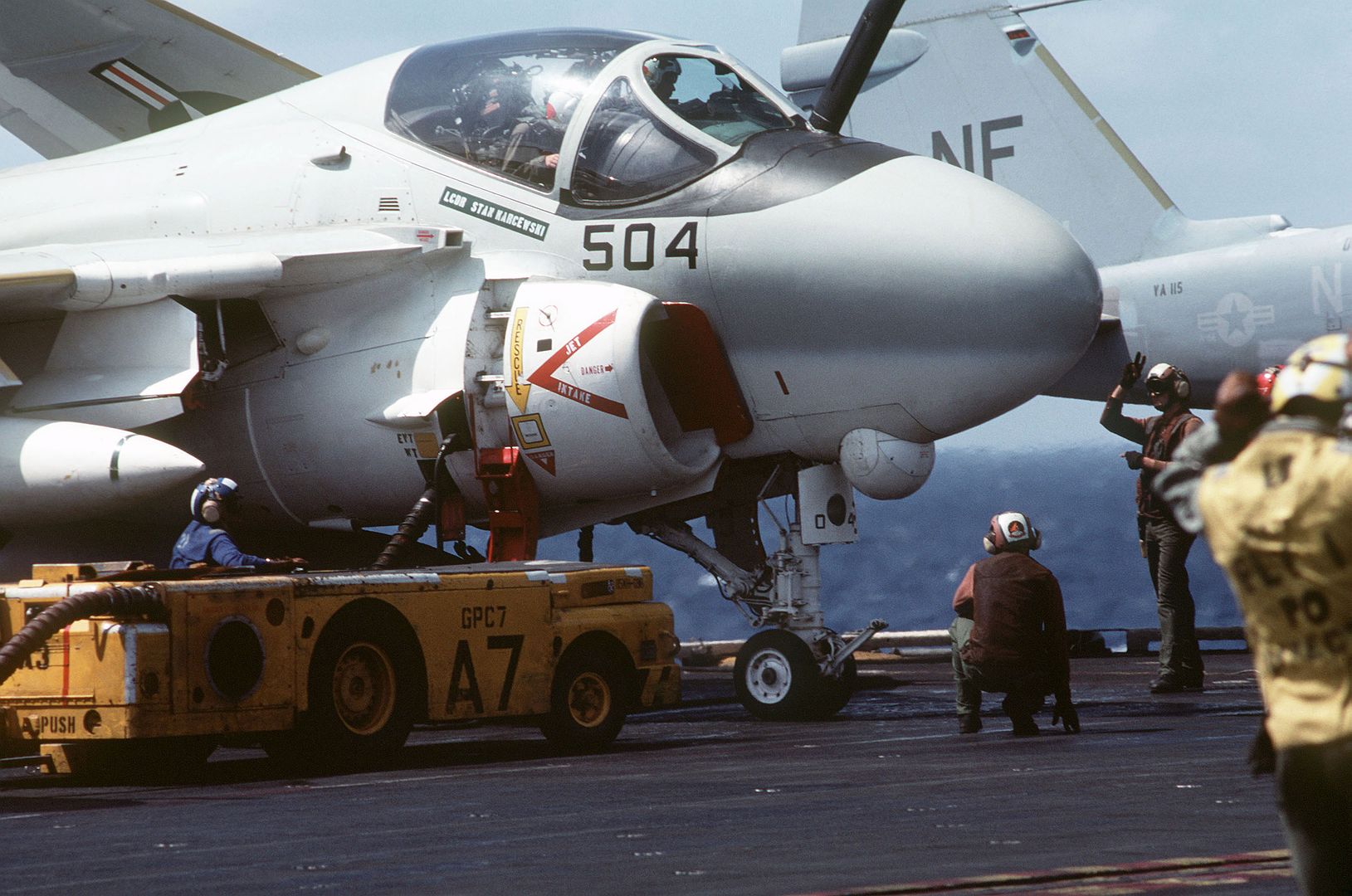 An MD 3A Tow Tractor Is Used As An A 6E Intruder Aircraft Is Serviced Prior To Takeoff Aboard The Aircraft Carrier USS MIDWAY 1