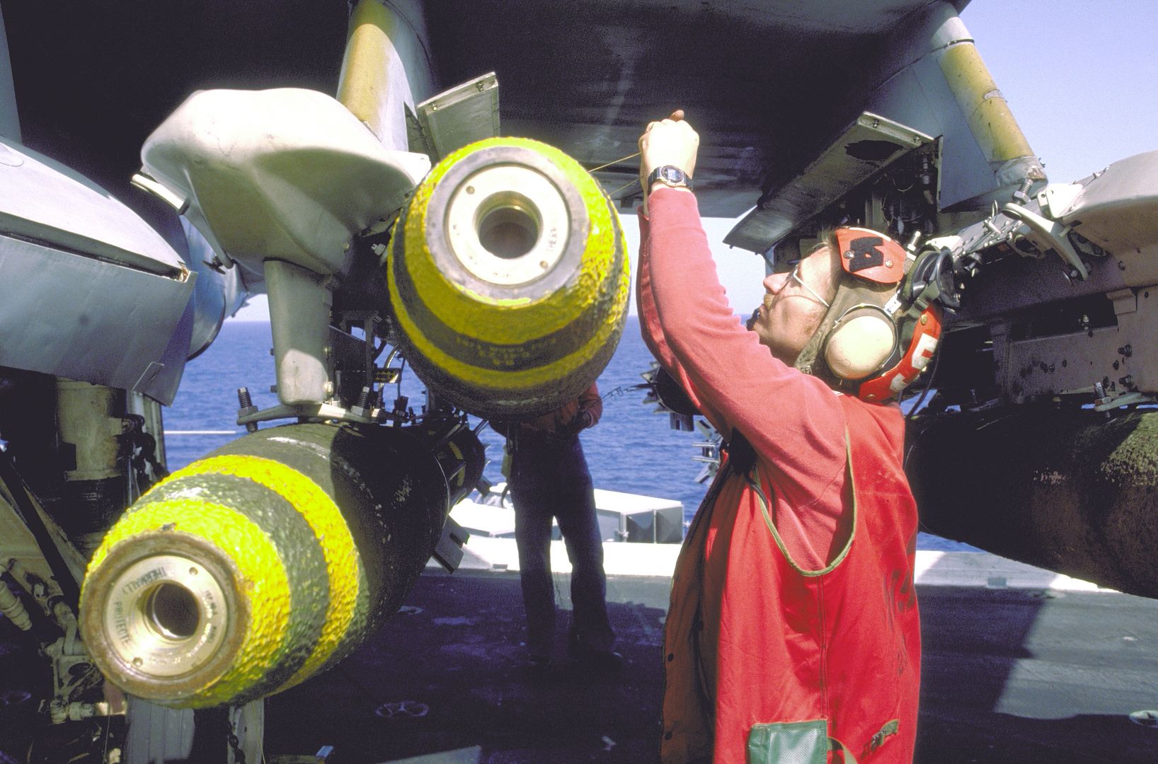 An Ordnance Crew Member From Attack Squadron 165 Mounts Mark 82 500 Pound Bombs Onto An A 6E Intruder Aircraft Aboard The Aircraft Carrier USS KITTY HAWK