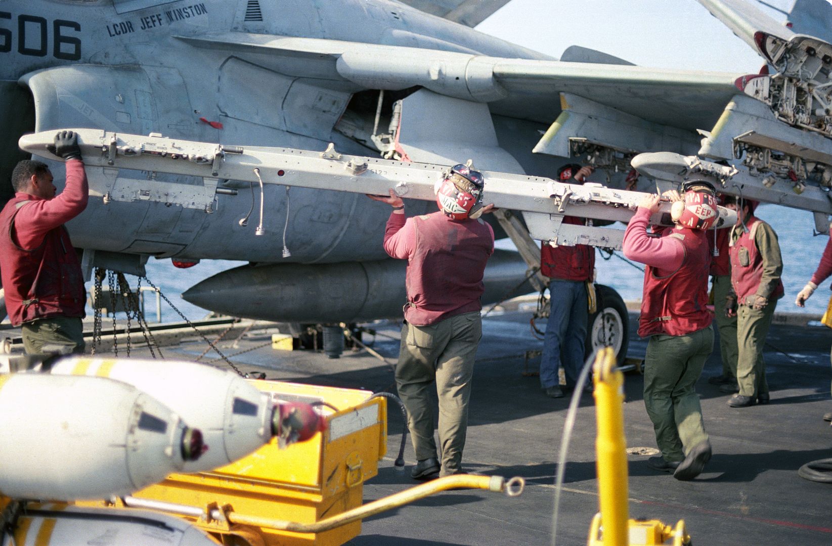 Aviation Ordnancemen From Attack Squadron 55 Attach A Bomb Rack To The Wing Of An A 6E Intruder Aircraft On The Flight Deck Of The Aircraft Carrier USS CORAL SEA