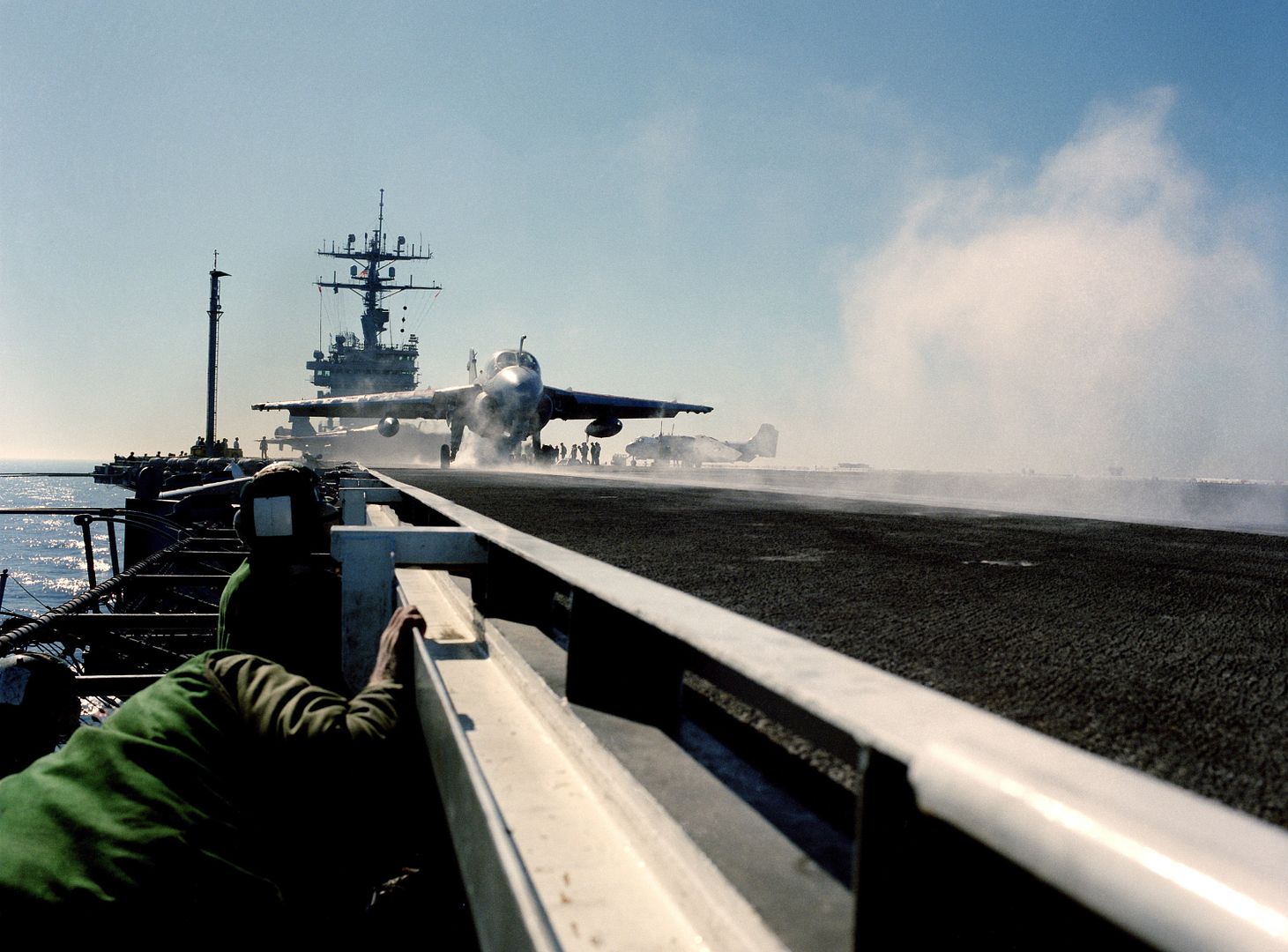 Flight Deck Crewman On A Catwalk Lower Their Heads As An A 6E Intruder Aircraft Is Launched From The Nuclear Powered Aircraft Carrier USS CARL VINSON