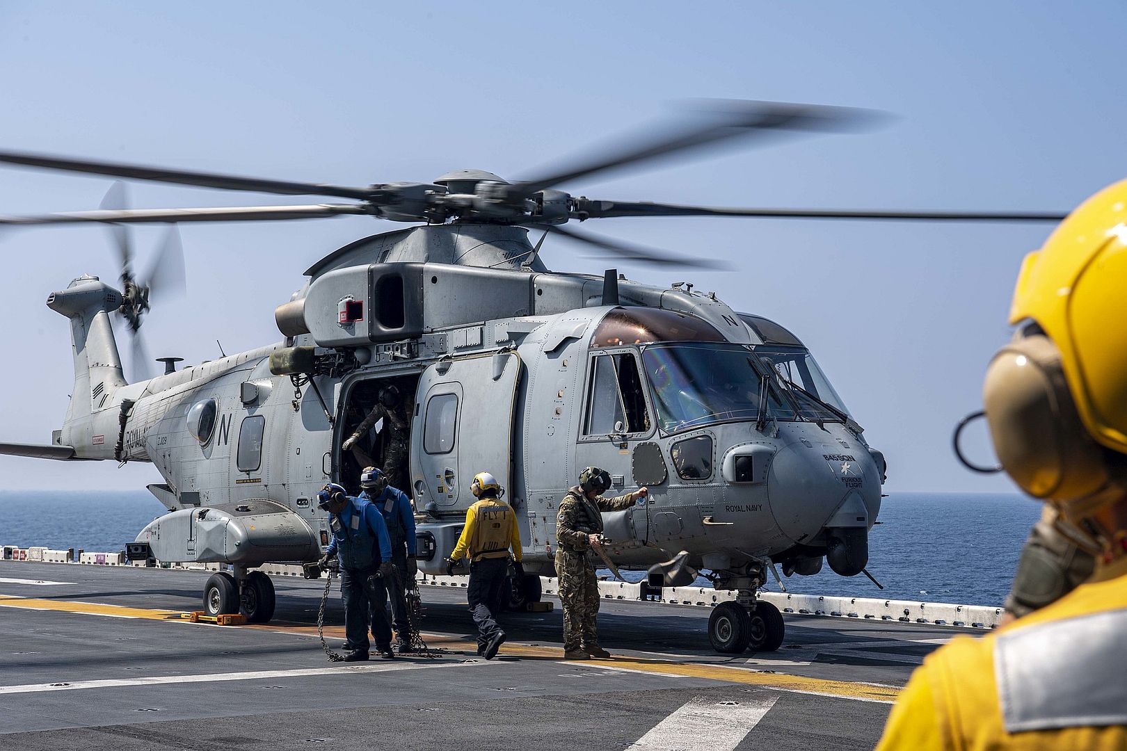Merlin Mk4 Attached To 845 Naval Air Squadron Deployed With The Royal Navy Aircraft Carrier HMS Queen Elizabeth On The Flight Deck Of The Amphibious Assault Ship USS Essex