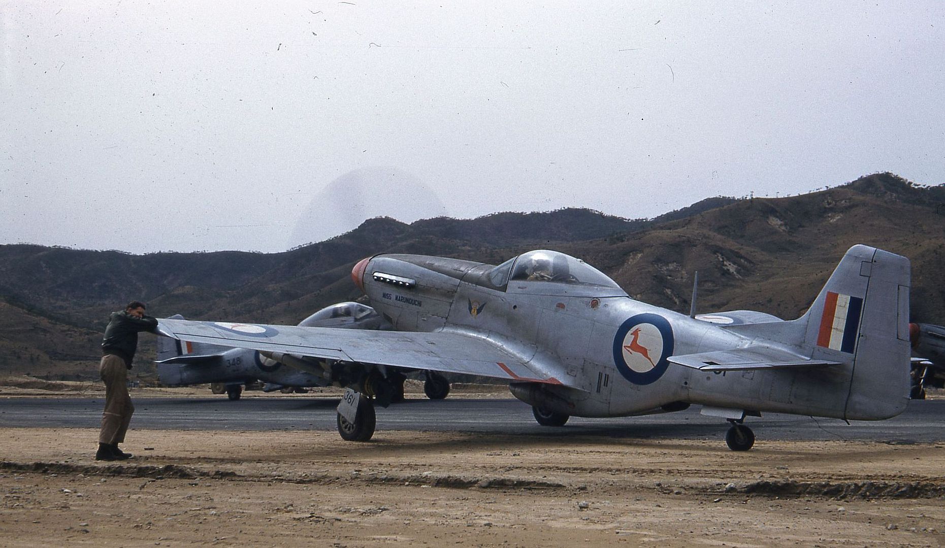 One_half_left_rear_view_of_a_North_American_Mustang_Mk._IVA_Miss_Marunouchi_sn_KM361_parked_beside_the_runway_somewhere_in_Korea..jpg